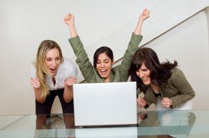 Imagen en la que refleja a 3 personas enfrente de un ordenador con alegría